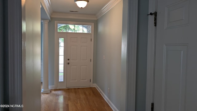 foyer entrance featuring crown molding, hardwood / wood-style floors, and ornate columns