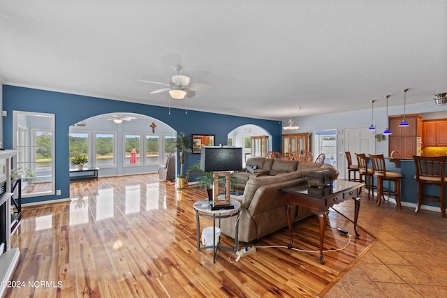 living room featuring light wood-type flooring, ceiling fan, and a textured ceiling