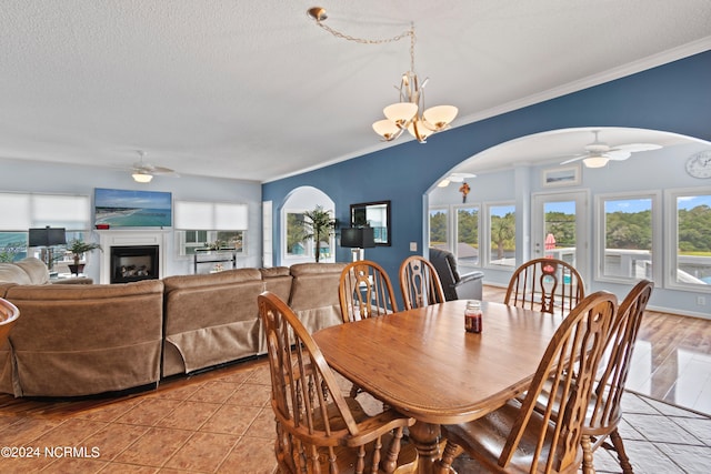 tiled dining room featuring a textured ceiling, ceiling fan with notable chandelier, and ornamental molding