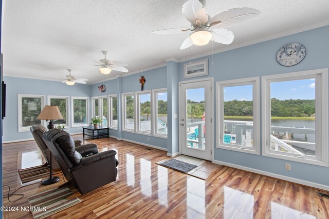 living room featuring a textured ceiling, light hardwood / wood-style floors, ceiling fan, and crown molding