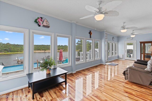 sunroom with a healthy amount of sunlight, a water view, and ceiling fan