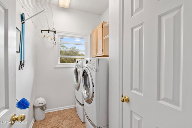 laundry area featuring cabinets, light tile patterned floors, and washer and clothes dryer