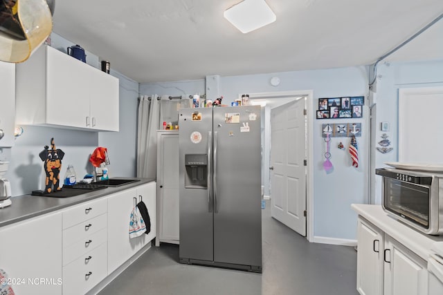 kitchen featuring stainless steel fridge and white cabinetry