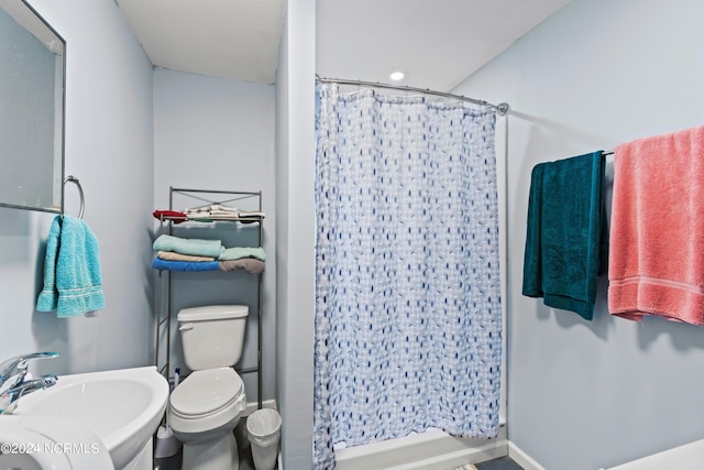 bathroom featuring walk in shower, toilet, and sink