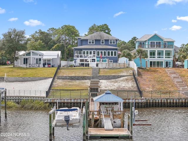 view of dock with a lawn, a water view, and a balcony