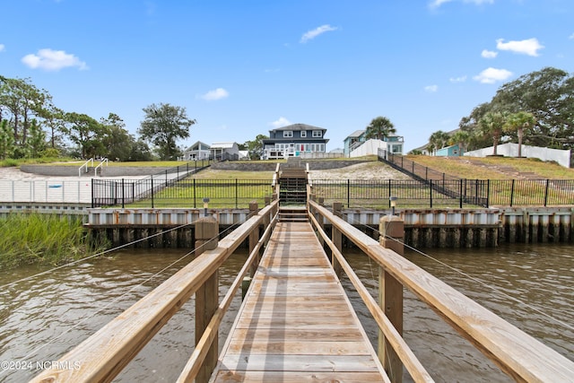 view of dock with a lawn and a water view