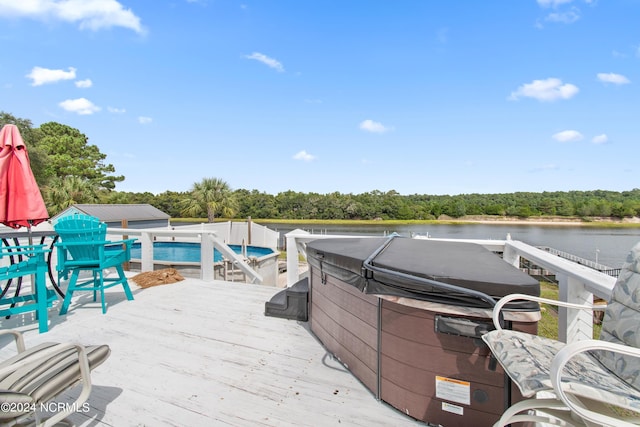 wooden deck featuring a pool with hot tub and a water view