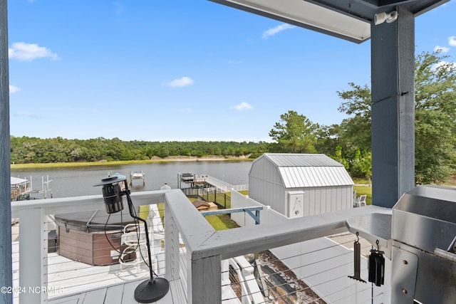 wooden terrace featuring a storage shed, a grill, and a water view