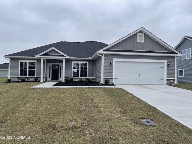 craftsman-style house with a front yard, stone siding, driveway, and an attached garage