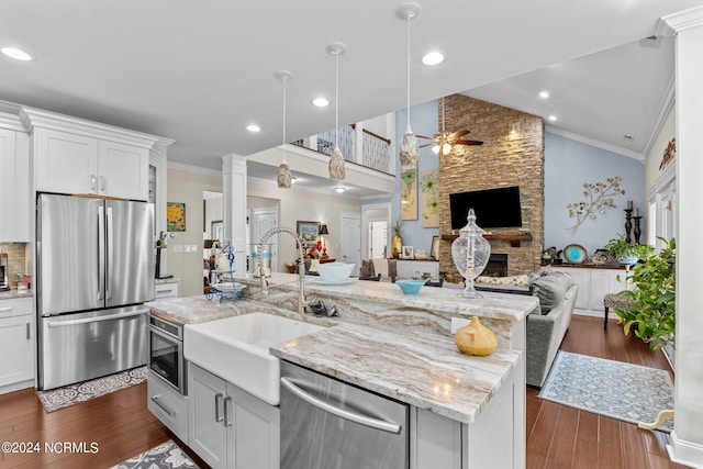 kitchen with a fireplace, stainless steel appliances, hanging light fixtures, and dark wood-type flooring