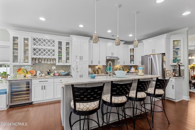 kitchen with beverage cooler, a center island with sink, white cabinets, a kitchen bar, and stainless steel refrigerator with ice dispenser