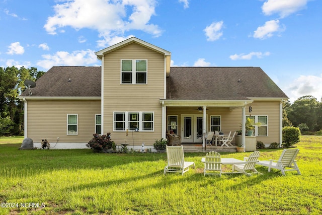 back of property with a yard, ceiling fan, and french doors