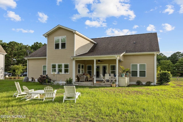 rear view of property featuring ceiling fan, a yard, and a shingled roof