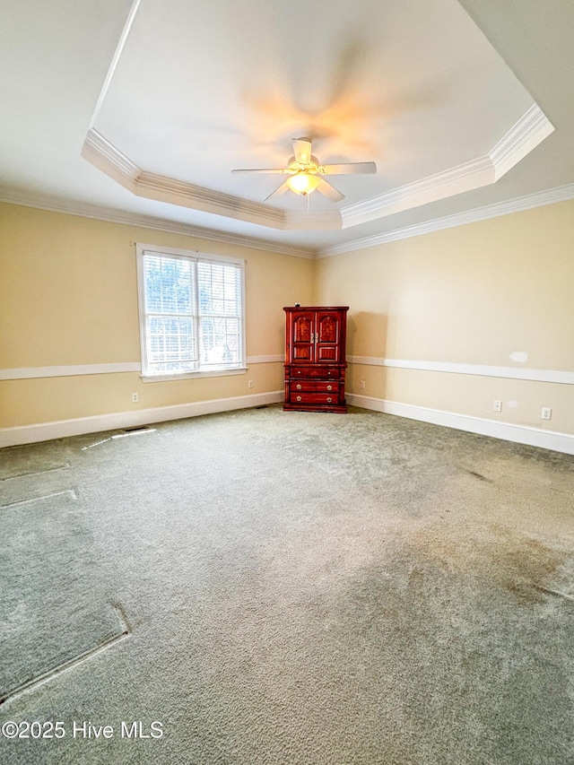 unfurnished room featuring a raised ceiling, a ceiling fan, baseboards, and carpet floors