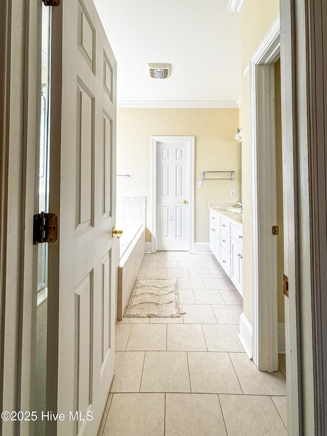 bathroom featuring tile patterned flooring, crown molding, baseboards, a bath, and vanity