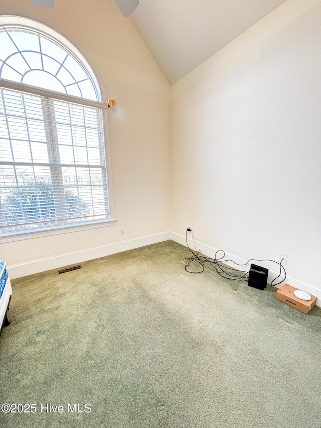 carpeted empty room with lofted ceiling, baseboards, and visible vents