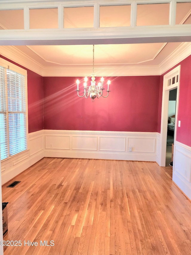 unfurnished dining area with a chandelier, visible vents, light wood-type flooring, and ornamental molding