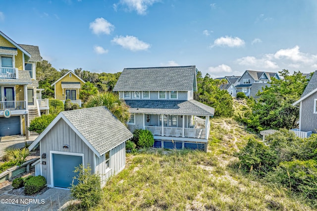 view of front facade featuring a porch, an outdoor structure, roof with shingles, a residential view, and board and batten siding