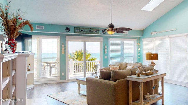 living room featuring hardwood / wood-style floors, ceiling fan, and lofted ceiling with skylight