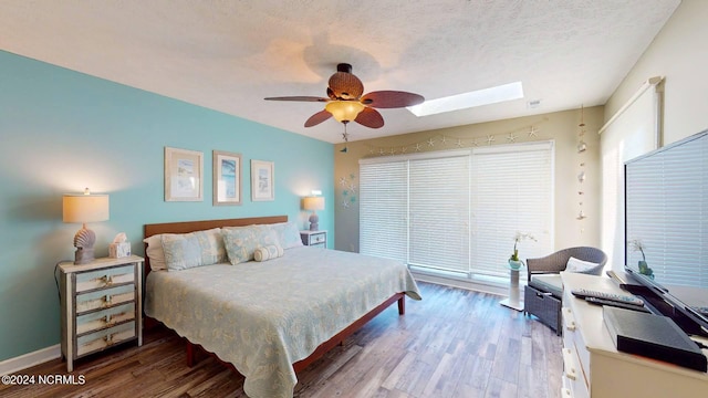 bedroom featuring a skylight, ceiling fan, hardwood / wood-style floors, and a textured ceiling