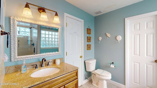 bathroom featuring tile patterned flooring, vanity, toilet, and walk in shower