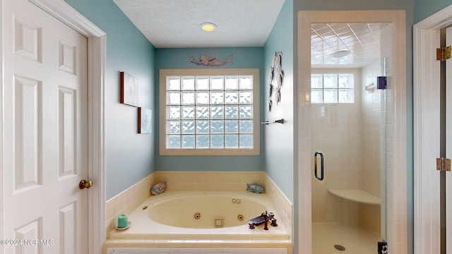 bathroom featuring independent shower and bath, a healthy amount of sunlight, and a textured ceiling