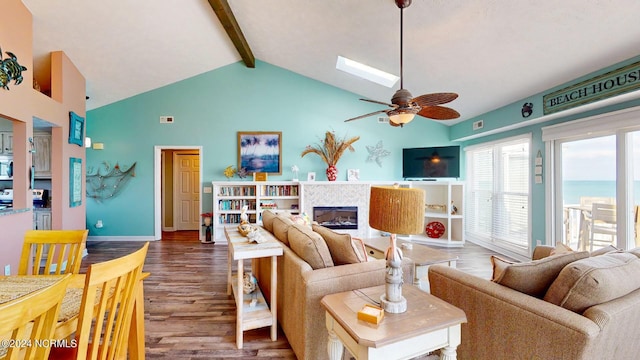 living room featuring a tile fireplace, a skylight, ceiling fan, beamed ceiling, and wood-type flooring