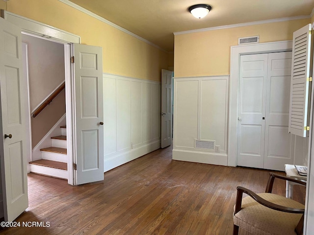 unfurnished bedroom with a closet, dark hardwood / wood-style floors, and crown molding