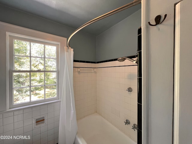 bathroom featuring tile walls and shower / bathtub combination with curtain