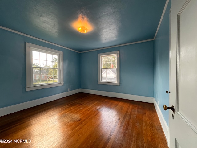 empty room with crown molding, hardwood / wood-style floors, a textured ceiling, and a healthy amount of sunlight