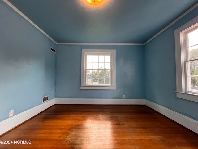 spare room with crown molding, hardwood / wood-style floors, and a wealth of natural light