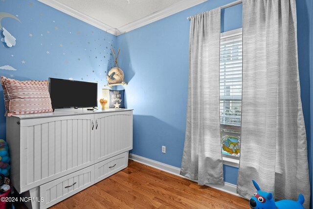 bedroom with a textured ceiling, crown molding, and hardwood / wood-style flooring