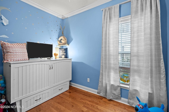 bedroom featuring baseboards, crown molding, and wood finished floors