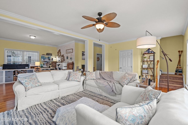 living area with ornamental molding, wood finished floors, ceiling fan, and stairs