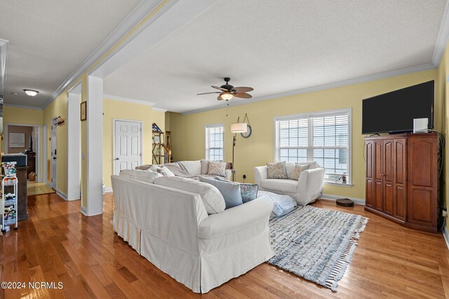 living room featuring ornamental molding, a textured ceiling, ceiling fan, and light hardwood / wood-style floors