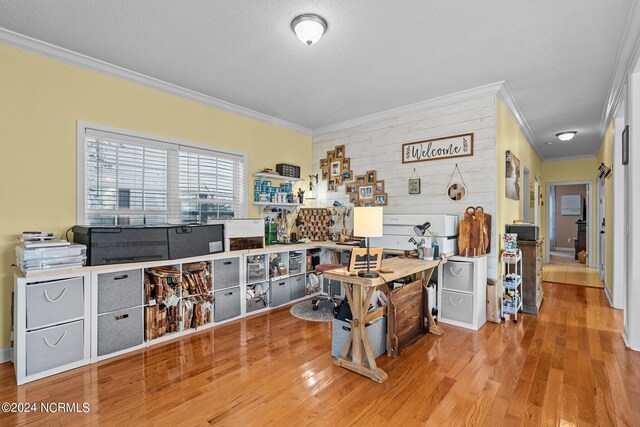 office space featuring light wood-type flooring, wood walls, a textured ceiling, and ornamental molding