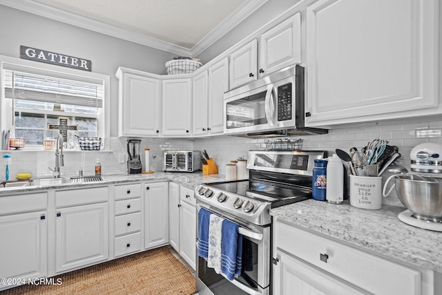 kitchen with stainless steel appliances, a sink, white cabinets, tasteful backsplash, and crown molding