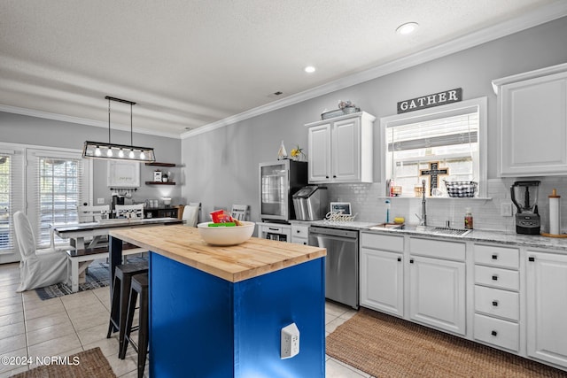 kitchen featuring butcher block countertops, backsplash, crown molding, stainless steel dishwasher, and a sink