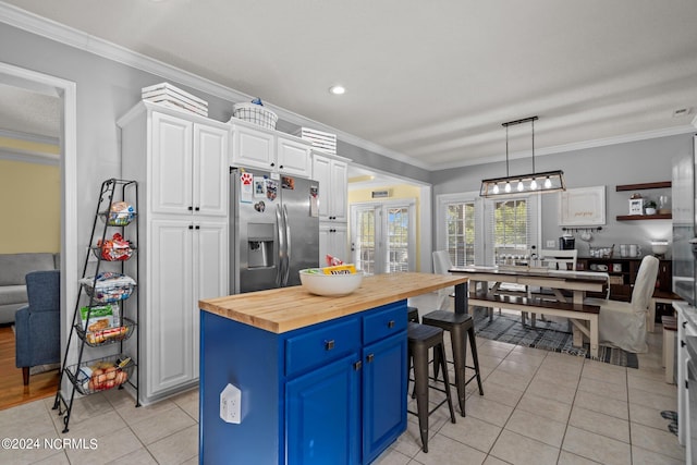 kitchen featuring stainless steel refrigerator with ice dispenser, blue cabinetry, ornamental molding, white cabinets, and butcher block countertops