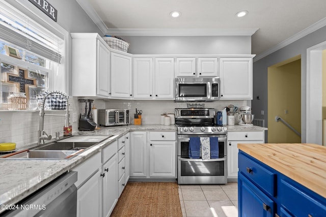 kitchen featuring stainless steel appliances, ornamental molding, wood counters, and white cabinetry