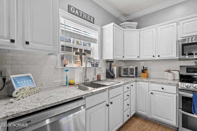 kitchen with white cabinets, appliances with stainless steel finishes, light stone counters, sink, and decorative backsplash