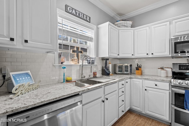 kitchen with stainless steel appliances, a sink, white cabinetry, ornamental molding, and backsplash