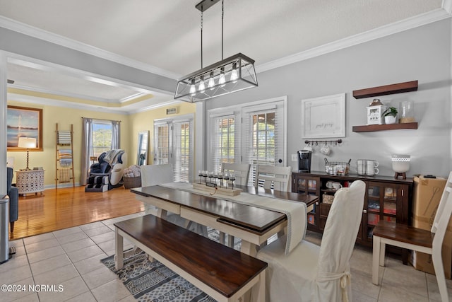 dining room featuring light wood-type flooring, a textured ceiling, a notable chandelier, and ornamental molding