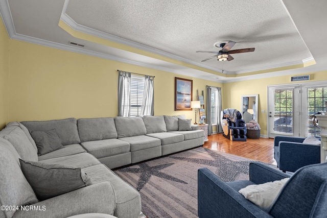 living area with ornamental molding, a tray ceiling, plenty of natural light, and wood finished floors