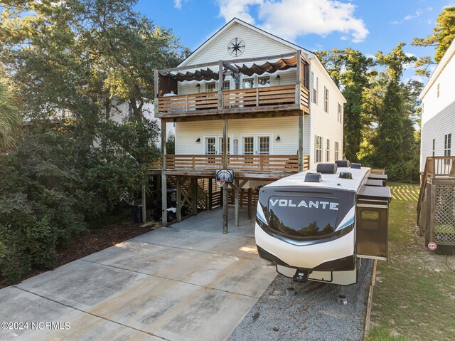 view of front of property with a balcony, a wooden deck, french doors, and a carport