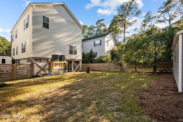 rear view of house featuring a fenced backyard, central AC, and a yard