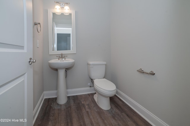 half bathroom with toilet, baseboards, and wood finished floors