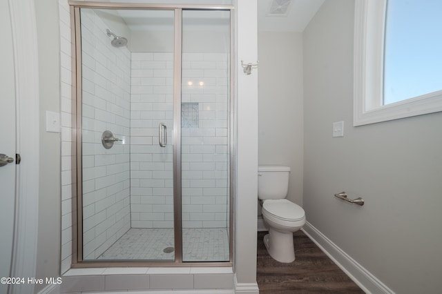 bathroom featuring toilet, wood finished floors, visible vents, baseboards, and a stall shower