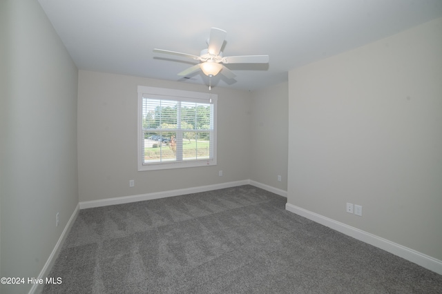 empty room featuring dark carpet, ceiling fan, and baseboards