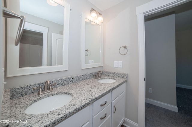 full bath with double vanity, a sink, and baseboards